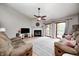 Cozy living room featuring a fireplace, ceiling fan, plush sofas, and sliding glass doors at 1630 Eastfork Dr, Brownsburg, IN 46112