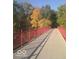 A scenic pedestrian bridge with red railings surrounded by lush autumn foliage at 1635 N College Ave # 4, Indianapolis, IN 46202