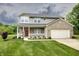 Charming two-story home featuring a covered front porch, red door, two-car garage, and a well-manicured lawn at 19187 Outer Bank Rd, Noblesville, IN 46062