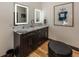 Modern bathroom features a double vanity with illuminated mirrors, artwork, and a stylish ottoman at 2004 Layton Rd, Anderson, IN 46011