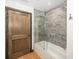 Well-lit bathroom featuring a shower-over-tub, marble-style tiling, and a rustic wooden door at 2004 Layton Rd, Anderson, IN 46011