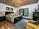 Cozy bedroom with wood-paneled ceiling, bright windows, rug, comfortable yellow chair, and bed at 2004 Layton Rd, Anderson, IN 46011