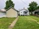 View of a private backyard featuring a detached garage, green grass, and mature trees at 2032 N Auburn St, Speedway, IN 46224