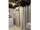 Basement bathroom with laundry sink and two shower areas with floral and plain curtains at 2032 N Auburn St, Speedway, IN 46224
