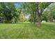 Scenic backyard view with lush green grass, mature trees, and a charming fence, offering a tranquil setting at 233 Saddlebrook Dr, Zionsville, IN 46077