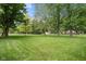 Lush green backyard with mature trees and a fenced perimeter, providing a private and spacious outdoor area at 233 Saddlebrook Dr, Zionsville, IN 46077