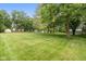 Spacious backyard showcasing a sprawling lawn, mature trees, and a fence line, creating a private oasis at 233 Saddlebrook Dr, Zionsville, IN 46077