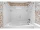 Bright bathroom featuring a white tub with a tiled surround and decorative wallpaper at 233 Saddlebrook Dr, Zionsville, IN 46077