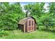 Backyard storage shed with double doors, surrounded by lush greenery and a well-maintained lawn at 3425 Ireland Dr, Indianapolis, IN 46235