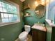 Bathroom with dark green walls, window, toilet, vanity and glass shower at 3520 Lantern Ln, Columbus, IN 47203