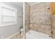 Updated bathroom features a tub and shower with tile surround and a window at 4048 N College Ave, Indianapolis, IN 46205