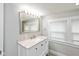 Bright bathroom with a marble countertop vanity, well-lit mirror, and a window providing natural light at 4048 N College Ave, Indianapolis, IN 46205
