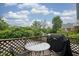 Back deck with a glass table and two chairs and a grill covered next to lush greenery at 5435 E 10Th St, Indianapolis, IN 46219