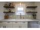 Kitchen sink features a window, open wood shelving, and patterned backsplash at 5435 E 10Th St, Indianapolis, IN 46219