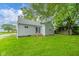 Backyard view of house with gray siding, sliding glass door, and a green lawn at 5516 W Minnesota St, Indianapolis, IN 46241