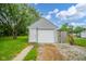 Detached one-car garage with white door and siding next to a grassy lawn and gravel driveway at 5516 W Minnesota St, Indianapolis, IN 46241