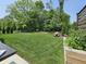 Sprawling green backyard features a rock water feature, mature trees, and manicured lawn at 5686 Ellie Ct, Noblesville, IN 46062