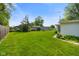 Lush backyard with green grass, mature trees, and a partial fence line under a bright blue sky at 623 Circle Ct, Whiteland, IN 46184