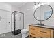 Bathroom with black fixtures, a walk-in shower, a round mirror, and a wood grain vanity at 631 1St Nw Ave, Carmel, IN 46032