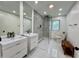 Modern bathroom featuring dual vanities, a glass-enclosed shower with stylish tiling, and ample natural light at 6519 Creekside Ln, Indianapolis, IN 46220
