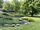 Landscaped front yard with decorative stone wall, foot bridge, and mature trees at 6519 Creekside Ln, Indianapolis, IN 46220