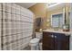 Cozy bathroom featuring patterned shower curtain, single sink vanity, and warm color palette at 6529 Lakesedge Dr, Indianapolis, IN 46237