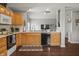 Open kitchen featuring dark wood floors, oak cabinets, dishwasher, and great lighting at 6529 Lakesedge Dr, Indianapolis, IN 46237