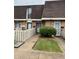 Inviting townhome exterior featuring a well-manicured lawn, picket fence, and brick facade at 7492 Country Brook Dr, Indianapolis, IN 46260