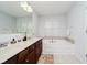 Bathroom featuring dual sinks, granite countertops, and a soaking tub at 755 Ivy Ln, Carmel, IN 46032