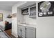 Basement wet bar with gray cabinets, sink, tile backsplash, and decorative shelving with decorative items at 8133 Lower Bay Ln, Indianapolis, IN 46236