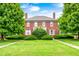 Charming two-story brick home with mature trees and a lush green lawn under a blue sky at 8436 E 56Th St, Indianapolis, IN 46216