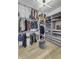 A well-organized walk-in closet with custom shelving, ample storage, a light wood floor, and a gray ottoman at 8695 Morgan Dr, Fishers, IN 46038