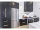 Well-equipped kitchen with stainless steel refrigerator, modern appliances, and sleek black cabinetry with gold hardware at 8695 Morgan Dr, Fishers, IN 46038