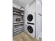 Laundry area featuring stacked washer/dryer, built-in storage, and light wood flooring and white walls at 8695 Morgan Dr, Fishers, IN 46038