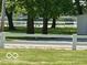 Lush backyard view featuring a white fence, mature trees, and serene lake in the background at 9451 S Amanda Dr, Claypool, IN 46510