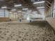 Spacious indoor riding arena with sand floor, wood beams, and tractor in background at 115 W State Road 38, Pendleton, IN 46064