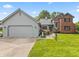 Charming two-story home with a grey garage, brick, beautiful landscaping, and a well-manicured lawn at 13153 Tudor Dr, Carmel, IN 46033