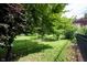 A backyard with a black metal fence surrounds a lush green lawn, adorned with mature trees and landscaping at 1477 Macintosh Ct, Avon, IN 46123