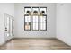 Bright, empty room with wood-look flooring, three large windows and modern light fixture at 1677 Solebar Way, Westfield, IN 46074