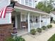 Inviting front porch with brick accents and white pillars, plants, seating, and American flag on display at 2303 Eagle Brook Dr, Shelbyville, IN 46176