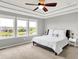 Bedroom featuring neutral tones, large windows overlooking a scenic view, and a tray ceiling with a ceiling fan at 2789 W High Grove Cir, Zionsville, IN 46077