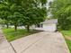 Quaint one-story house featuring an attached garage and a long driveway, surrounded by lush greenery at 308 Mohawk St, Anderson, IN 46012