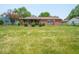 Expansive backyard featuring a well-maintained lawn and a classic brick home with a covered patio at 3303 Wedgewood Dr, Indianapolis, IN 46227