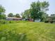 Large backyard with mature trees, storage sheds, brick house with covered patio, and a fenced area at 3303 Wedgewood Dr, Indianapolis, IN 46227