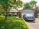 Quaint single-story home with a brick facade, lush green lawn, mature trees, and an attached two-car garage at 3303 Wedgewood Dr, Indianapolis, IN 46227