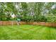 Spacious backyard features lush green grass, wooden fence, playset, mature trees, and a cozy fire pit at 3304 Fox Orchard Cir, Indianapolis, IN 46214