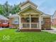 Charming brick home featuring a cozy front porch, landscaped lawn, and classic architectural details at 3558 N Gladstone Ave, Indianapolis, IN 46218