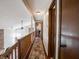 Upstairs hallway with hardwood floors, wood railing, and views of the living area below at 4382 Castlebay Way, Indianapolis, IN 46254