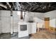 Basement laundry area with washer, dryer, and utility sink, featuring exposed ductwork and concrete floors at 4641 Crittenden Ave, Indianapolis, IN 46205