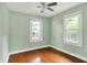 Bright bedroom featuring two windows, hardwood floors, a ceiling fan, and painted in a light sage color at 4641 Crittenden Ave, Indianapolis, IN 46205